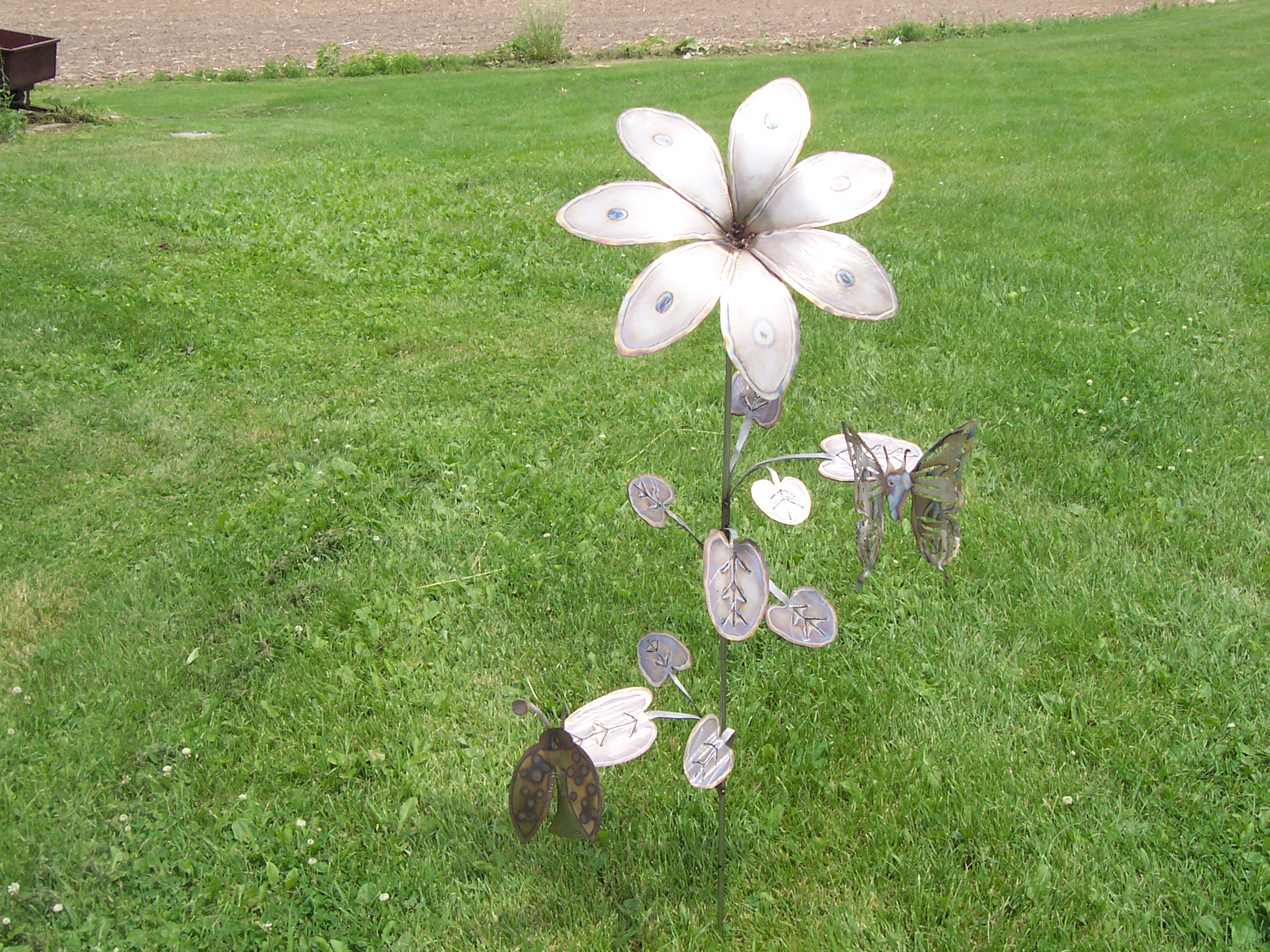 A bronze sculpture of a flower with two butterflys on the petals